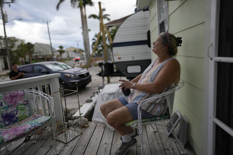 Jacquelyn Velazquez sits on the front porch of her family's home, which had to be gutted after Hurricane Ian sent storm waters to within inches of the ceiling and damaged the house's roof, in Fort Myers Beach, Fla., Wednesday, May 24, 2023. The Velazquez family feels lucky to have survived the storm, which they rode out on the second floor of a neighbor's home, and to be permitted by FEMA to rebuild their historic wooden house rather than tear it down. (AP Photo/Rebecca Blackwell)