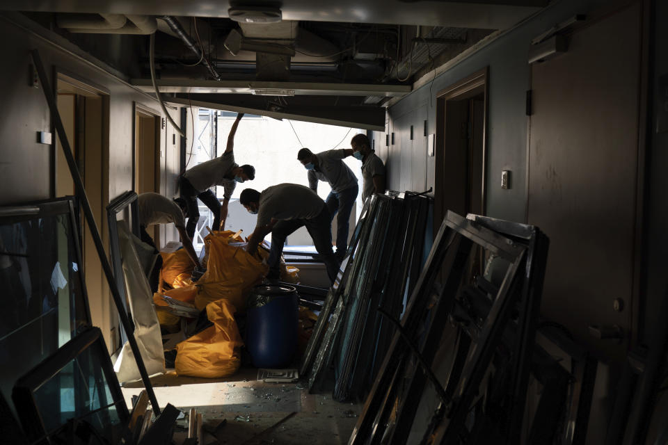 FILE - In this August 13, 2020 file photo, workers remove debris from the Saint George Hospital, that was heavily damaged in the Aug. 4 massive explosion in Beirut, Lebanon. Lebanon’s health services and facilities were once considered among the region’s best. But in a short time, they have been brought to near collapse, battered by Lebanon’s financial meltdown and a surge in coronavirus cases, then smashed by the Beirut explosion. (AP Photo/Felipe Dana, File)