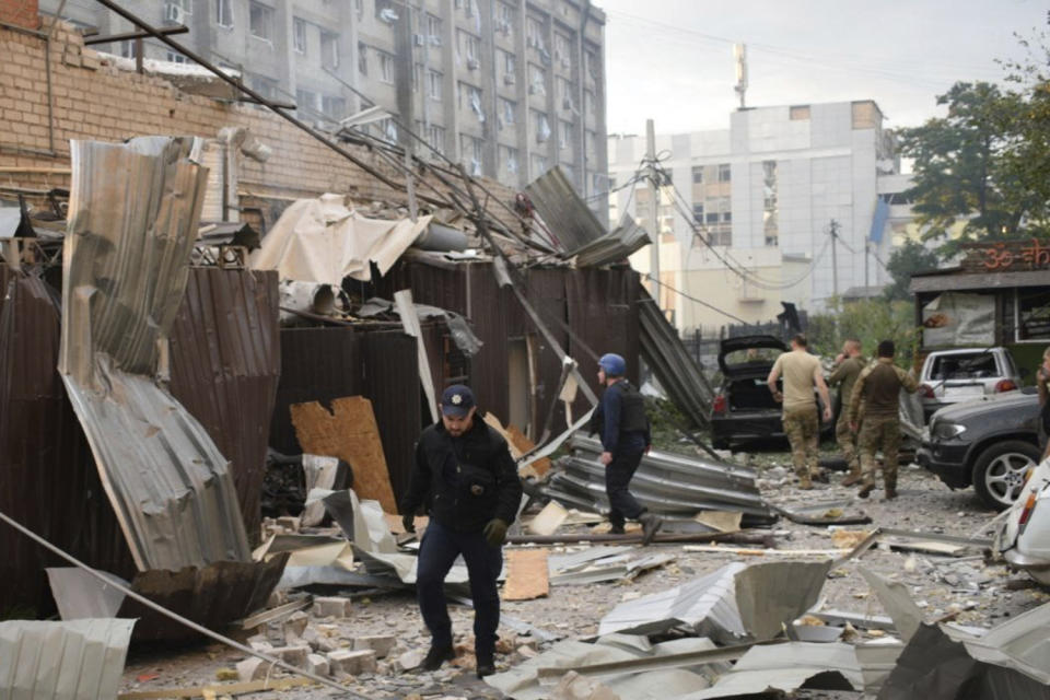 In this photo provided by the National Police of Ukraine, a police officer and a rescue worker walk in front of a restaurant RIA Pizza destroyed by a Russian attack in Kramatorsk, Ukraine, Tuesday, June 27, 2023. (National Police of Ukraine via AP)