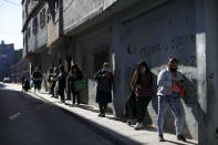 Women stand in line to receive food from a soup kitchen at the 1.11.14 slum during a government-ordered lockdown to curb the spread of the new coronavirus, in Buenos Aires, Argentina, Tuesday, May 26, 2020. (AP Photo/Natacha Pisarenko)