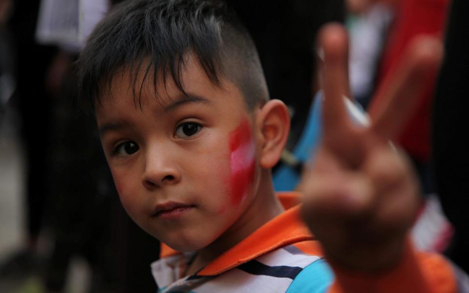  A member of Peruvian community living in Chile makes a two-finger salute as he attends a rally to support their compatriots in Santiago - REUTERS