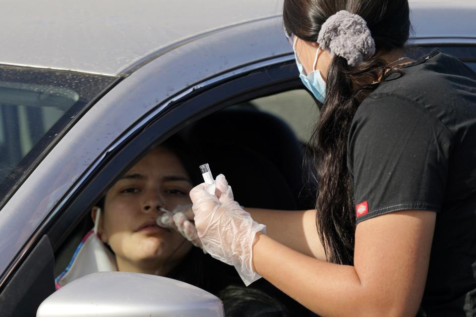 A healthcare worker performs a COVID-19 test at a drive-thru testing center Tuesday, Dec. 8, 2020, in Phoenix. Arizona on Tuesday set a new daily record with over 12,300 additional known coronavirus cases as the number of hospitalized patients approached levels similar to the peak of last summer's surge, with the state's seven-day rolling average continuing to climb in the past two weeks as have the rolling averages for daily deaths and daily COVID-19 testing positivity. (AP Photo/Ross D. Franklin)