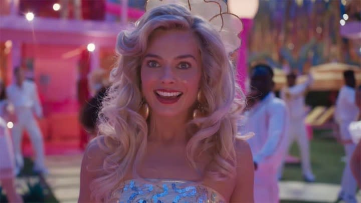 Margot Robbie as Barbie with a confused expression while at a party in Barbie.