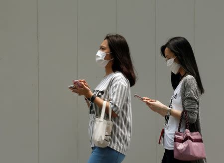 Women wearing face masks use their mobile phones as haze shrouds Singapore's central business district August 26, 2016. REUTERS/Edgar Su