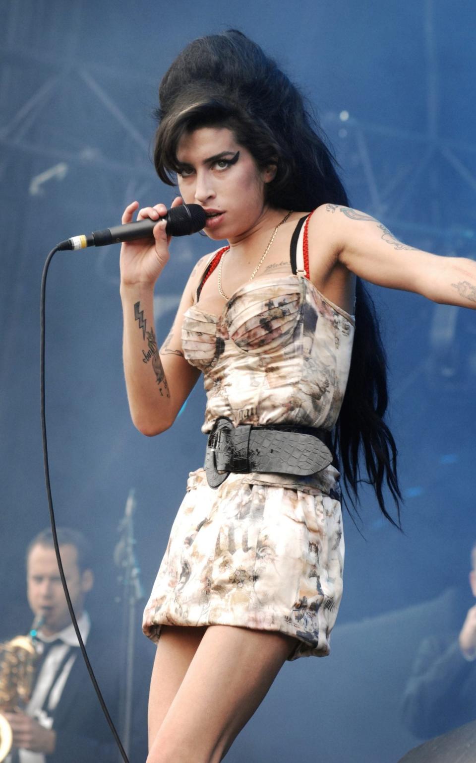 Winehouse performing in her quintessential look: the beehive, the eyeliner, the minidress and the tattoos