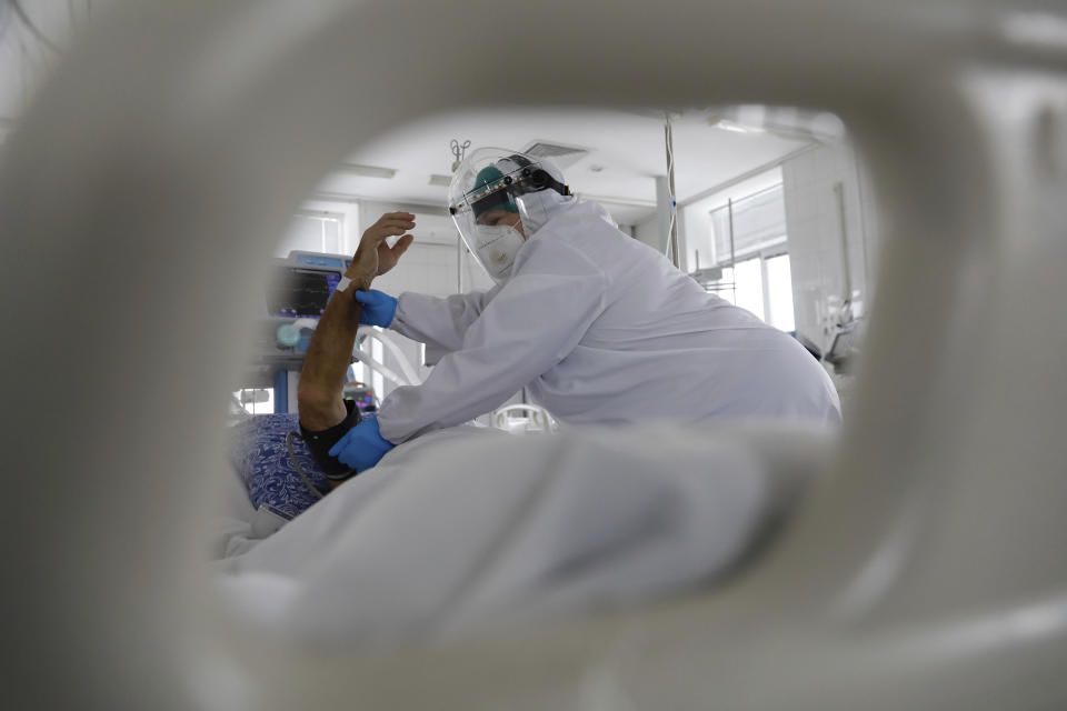 A medical staff member wearing special suits to protect against coronavirus treats a patient with coronavirus at an ICU of the Clinical hospital in Volgograd, Russia, Monday, Jan. 31, 2022. Russia's state coronavirus task force reported a total of 11.8 million confirmed cases in the pandemic and 331,349 deaths — by far the highest death toll in Europe. However, reports by Russia's state statistics service Rosstat, which uses wider criteria for counting virus-linked deaths, revealed much higher numbers. (AP Photo/Alexandr Kulikov)