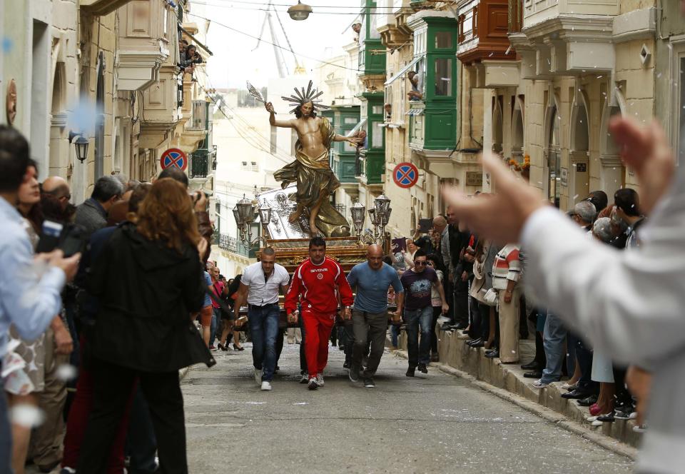 Worshippers run while carrying a statue of the Risen Christ during an Easter Sunday procession in Cospicua