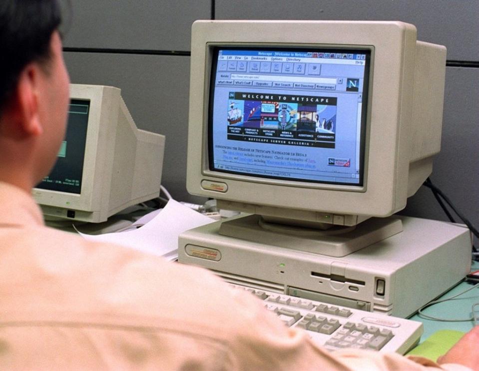 Person at a computer with a bulky monitor displaying the Netscape Navigator browser; a nod to early internet days