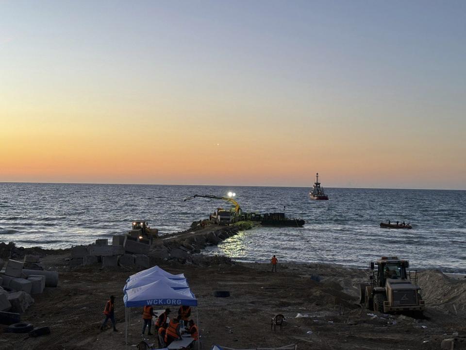 This photo provided by World Central Kitchen shows a crane unloading food packages over a makeshift port on the Gaza Strip, Saturday, March 16, 2024. Spanish NGO Open Arms has sent essential aid to Gaza by a barge towed by a ship from Cyprus. The food was sent by World Central Kitchen, the charity founded by celebrity chef José Andrés, which operates kitchens providing free meals in Gaza. WCK said that it was offloading almost 200 tons of rice, flour and proteins on Saturday and that a second vessel is preparing to set sail from Cyprus with hundreds more tons of food. (World Central Kitchen via AP)