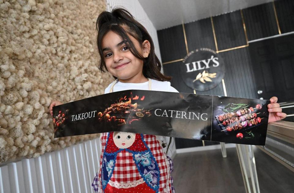 Gevork “George” Mkrtchyan and his wife Sara Sulukyan’s daughter daughter Lily, 6, holds a banner of the new Mediterranean take-out restaurant Lily’s Kitchen & Catering, which opened in September this year at Bullard and West avenues.
