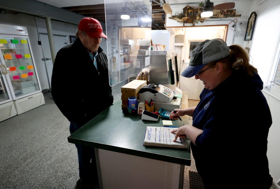 Customer Darrell Seegmiller, 75, of Hemlock, left, and Lakon Williams, co-owner of the Bay Port Fish Company in Bay Port, go over his order of smelt fish at the counter on Wednesday, May 4, 2022.