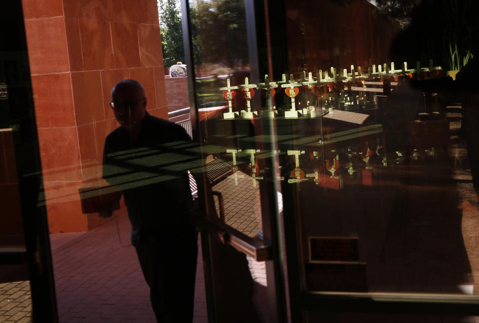 In this Sept. 25, 2018, photo, a man walks near a display of wooden crosses and Star of David at the Clark County Government Center in Las Vegas. The crosses and Star of David had been part of a makeshift memorial along the Las Vegas Strip erected in memory of the victims of the Oct. 1, 2017, mass shooting in Las Vegas. (AP Photo/John Locher)