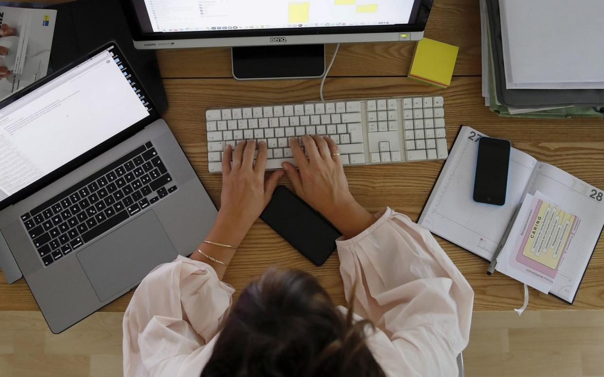 A woman works at a desktop computer alongside an Apple Inc. laptop in a home office  - Stefan Wermuth /Bloomberg
