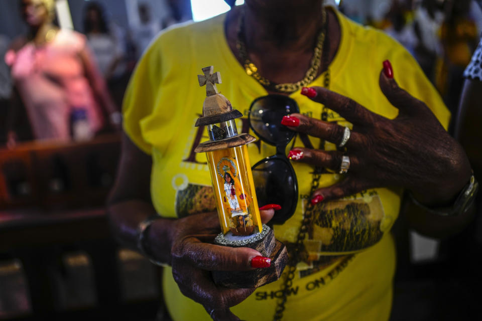 Una mujer sostiene una estatuilla de la Virgen de la Caridad del Cobre durante una misa en el santuario de El Cobre, Cuba, el domingo 11 de febrero de 2024. (AP Foto/Ramón Espinosa)