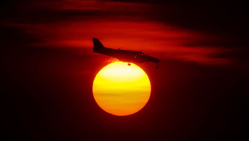 A plane passes in front of the glowing sun as it makes its final approach at the Salt Lake City International Airport on Monday, Oct. 5, 2020.