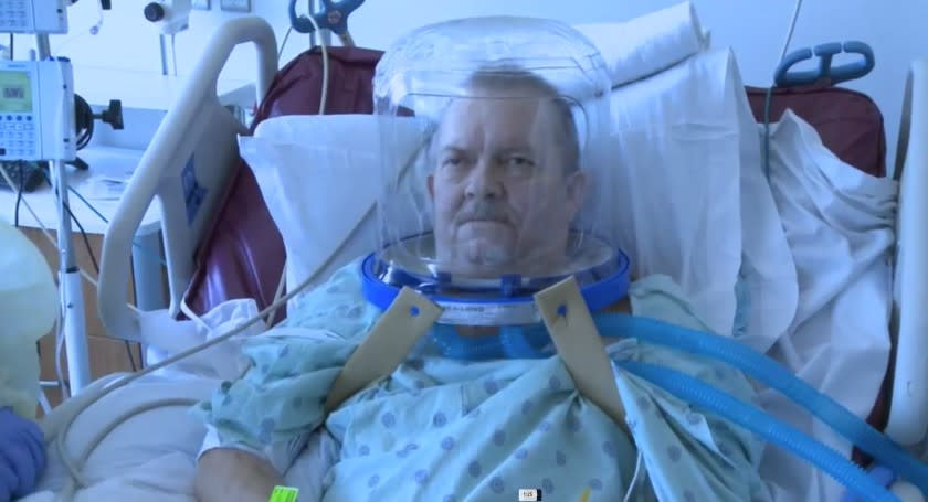 A patient wearing a helmet-based ventilation device.