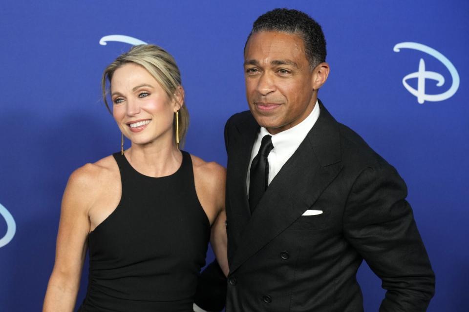 Amy Robach and T.J. Holmes pose together in semiformal attire