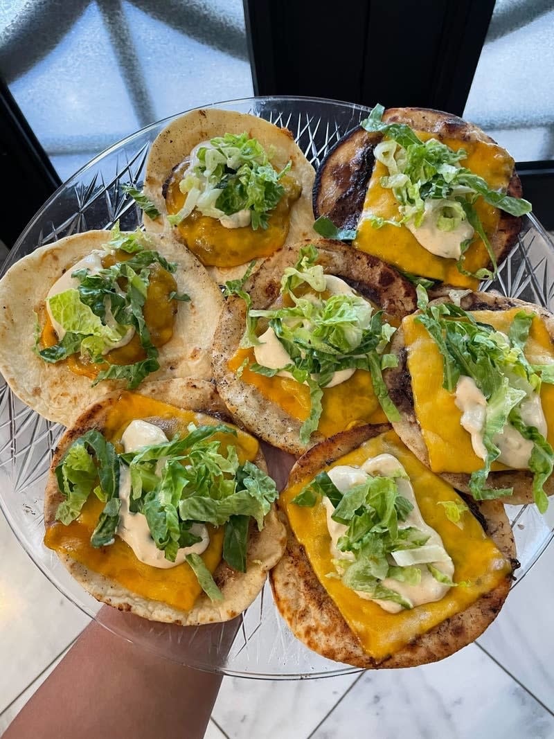 author holding out tray of big mac tacos with cheese, mac sauce, and shredded lettuce