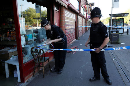 Police officers tie up cordon tape outside a barber's shop in Moss Side which was raided by officers in Manchester, Britain, May 26, 2017. REUTERS/Darren Staples