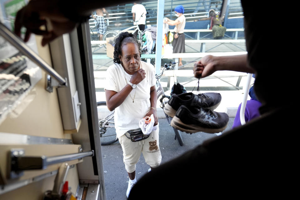 A homeless woman is given a pair of shoes from a nurse working aboard one of five Circle The City mobile clinics stationed outside soup kitchens and other services for homeless people, Thursday, May 30, 2024 in Phoenix. Based in the hottest big metro in America, Circle the City is taking measures to protect patients from life-threatening heat illness as temperatures hit new highs. Homeless people accounted for nearly half of the record 645 heat-related deaths last year in Arizona's Maricopa County, which encompasses metro Phoenix.(AP Photo/Matt York)