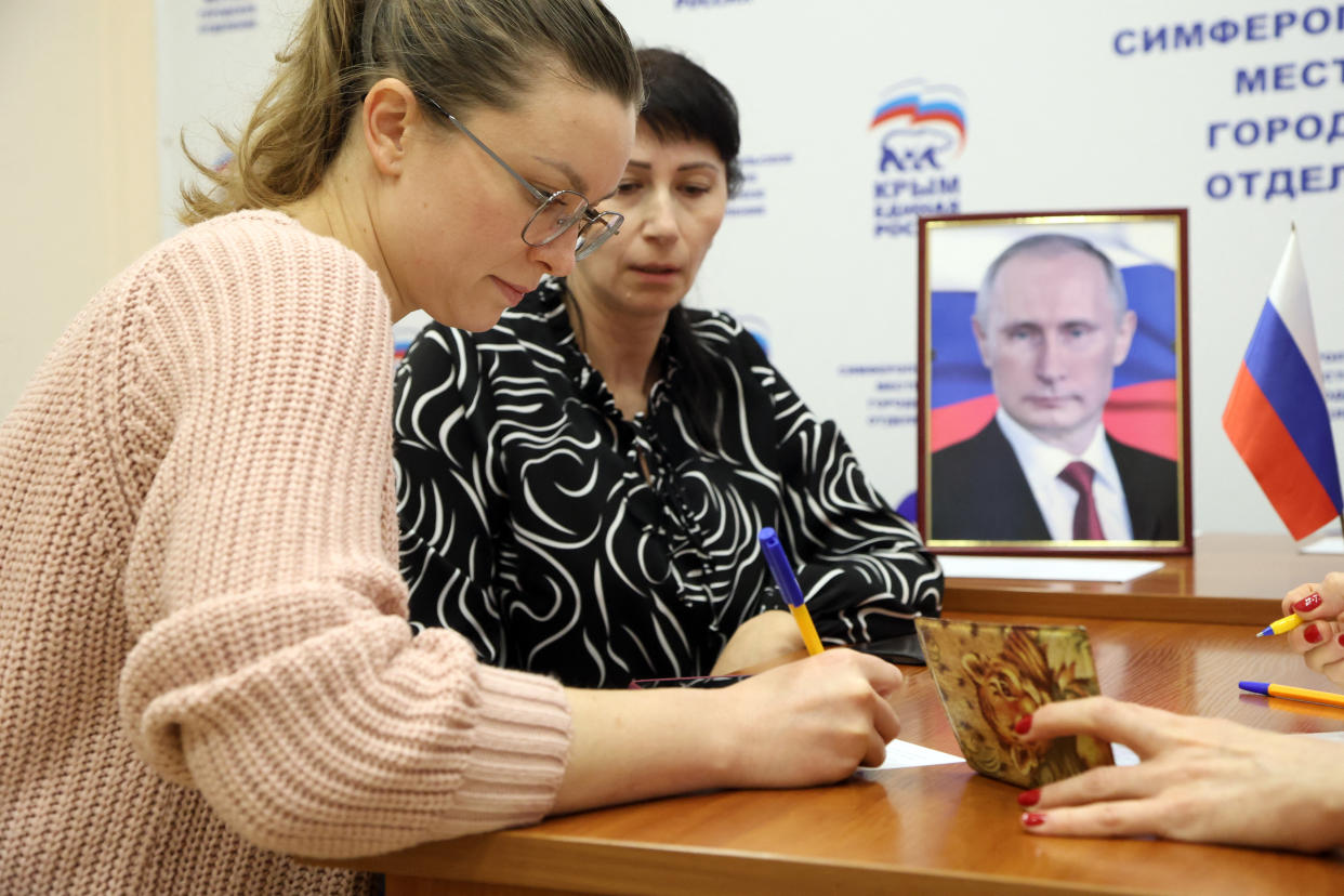 A woman fills out a form in support of Vladimir Putin in occupied Crimea. (AP)