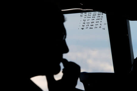 FILE PHOTO: A crew member aboard a Royal New Zealand Air Force P-3K2 Orion aircraft is pictured alongside handwritten notes of other search craft in the area, during a search for the missing Malaysian Airlines flight MH370 over the southern Indian Ocean, March 29, 2014. REUTERS/Jason Reed/File Photo