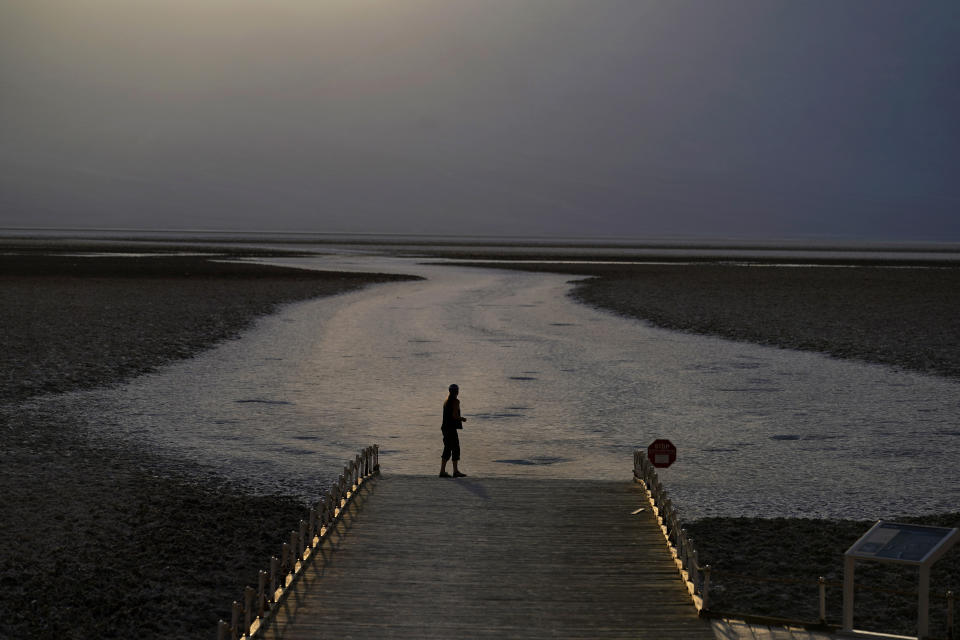 FILE - In this Aug. 17, 2020, file photo, a person walks on a boardwalk at the salt flats at Badwater Basin, in Death Valley National Park, Calif. Death Valley recorded a scorching 130 degrees (54.4 degrees Celsius) the day before. This year has seen record Atlantic hurricanes and western wildfires, devastating floods in Asia and Africa and a hot, melting Arctic. It's not just been a disastrous year, but a year of disasters. (AP Photo/John Locher, File)