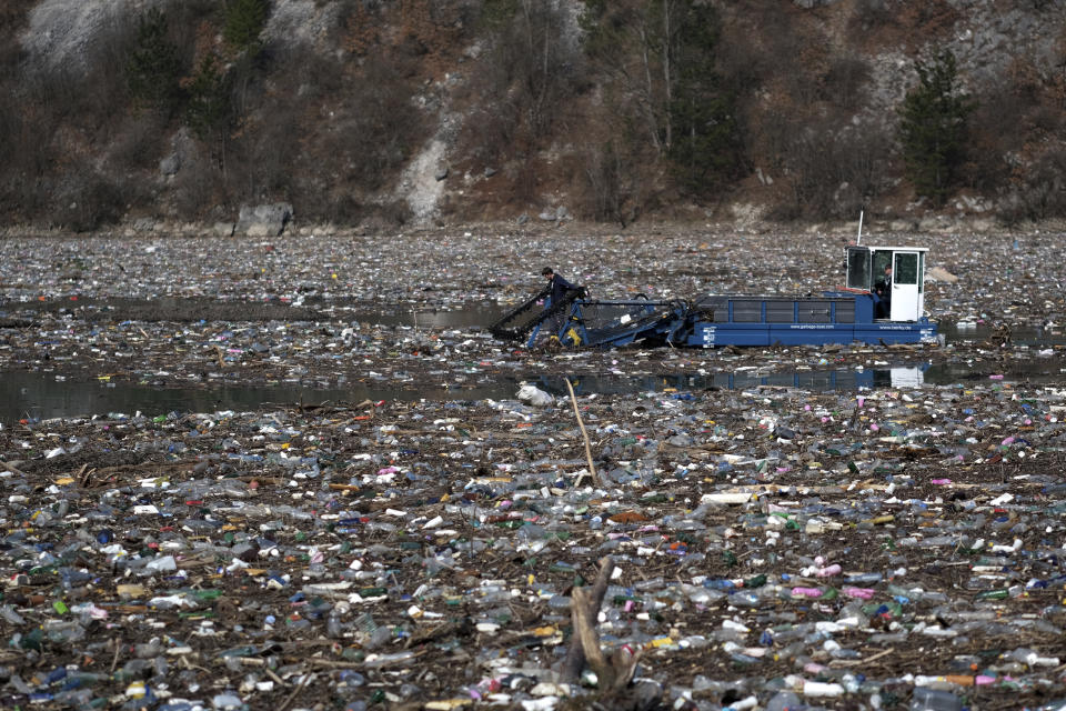 A machine collects garbage floating in the Drina river near Visegrad, eastern Bosnia, Wednesday, Feb. 24, 2021. Environmental activists in Bosnia are warning that tons of garbage floating down the Balkan country's rivers are endangering the local ecosystem and people's health. The Drina River has been covered for weeks with trash that has piled up faster than the authorities can clear it out. (AP Photo/Kemal Softic)