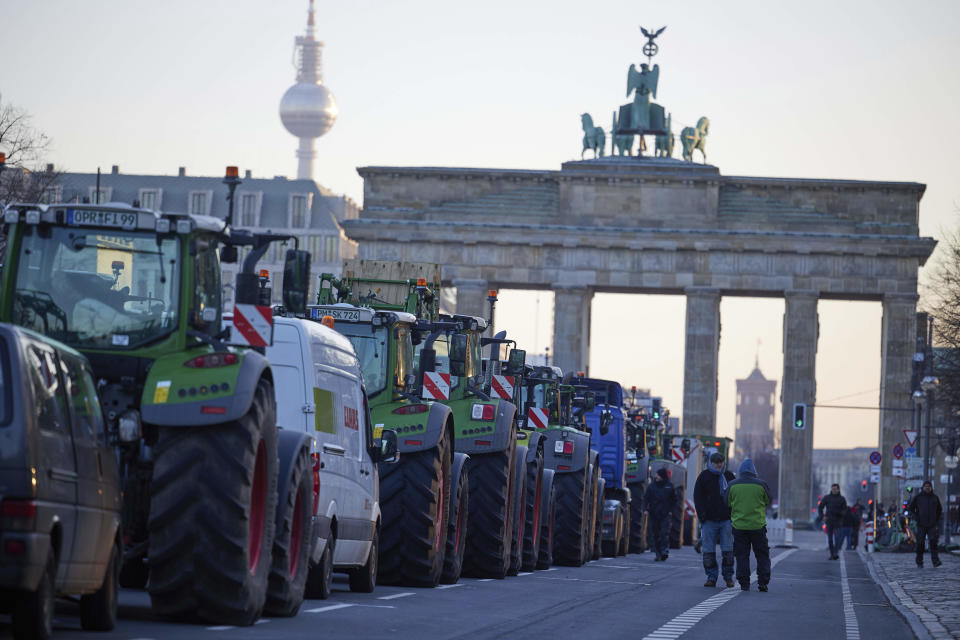 Numerous tractors stand in front of the Brandenburg Gate during a farmers' protest in Berlin, Germany, Monday, Jan. 8, 2024. Farmers blocked highway access roads in parts of Germany Monday and gathered for demonstrations, launching a week of protests against a government plan to scrap tax breaks on diesel used in agriculture. (Joerg Carstensen/dpa via AP)