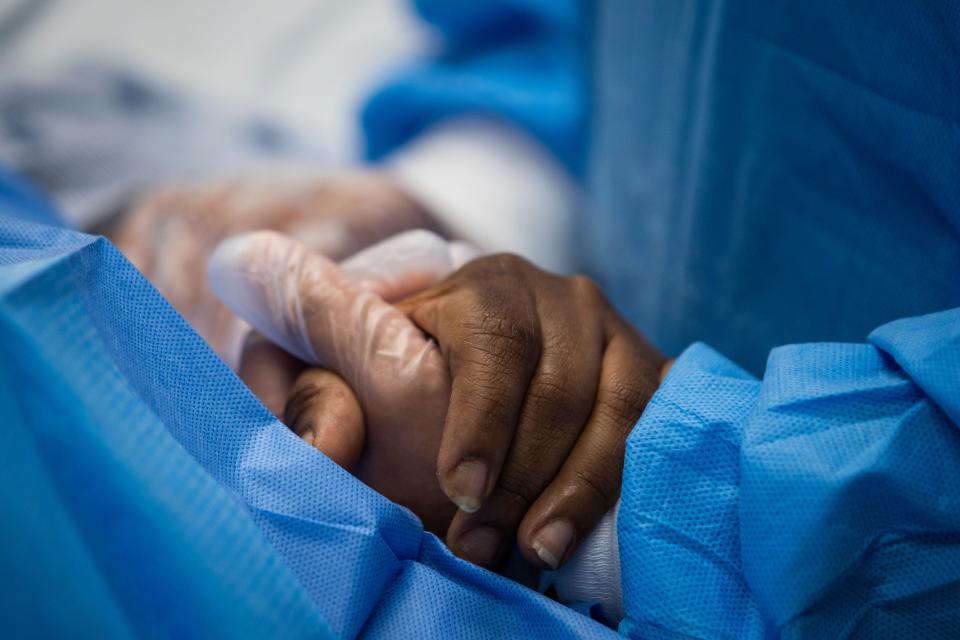 In this April 28, 2020, file photo, nurse practitioner talks to a patient and holds her hand while a doctor administers an IV at Roseland Community Hospital in Chicago. Many African Americans watching protests calling for easing restrictions meant to slow the spread of the new coronavirus see them as one more example of how their health and their just don't seem to matter.