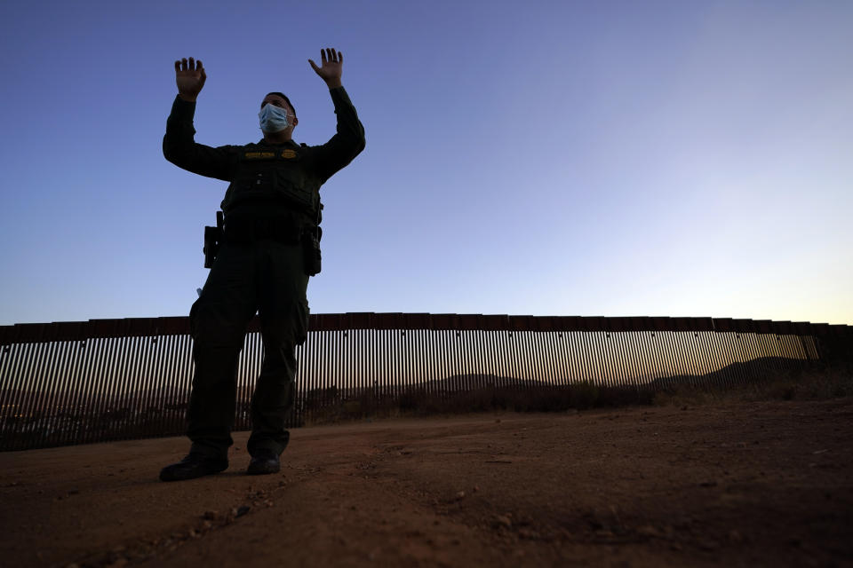 Border Patrol agent Justin Castrejon gestures as he describes the difficulties of climbing the new section of the border structure, behind, Thursday, Sept. 24, 2020, near Tecate, Calif. President Donald Trump’s reshaping of U.S. immigration policy may be most felt in his undoing of asylum. Castrejon says migrants pay $8,000 to $10,000 to be guided through the mountains and picked up by a driver once they reach a road. (AP Photo/Gregory Bull)