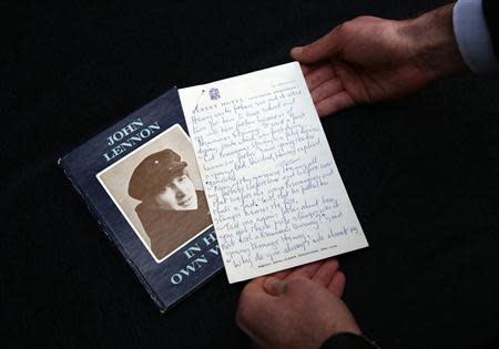 A manuscript written by John Lennon entitled 'Henry and Harry' is held for the cameras by a Sotheby's employee, London March 21, 2014. REUTERS/Paul Hackett