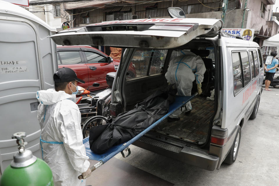 Funeral workers wearing protective suits carry a person who died due to COVID-19 complications at a hospital in Manila, Philippines on Monday, April 26, 2021. COVID-19 infections in the Philippines surged past 1 million Monday in the latest grim milestone as officials assessed whether to extend a monthlong lockdown in Manila and outlying provinces amid a deadly spike or relax it to fight recession, joblessness and hunger. (AP Photo/Aaron Favila)