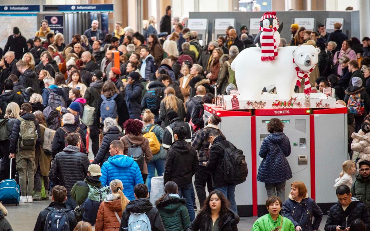 People wait on the concourse of St Pancras train station as thousands begin their journey out of London