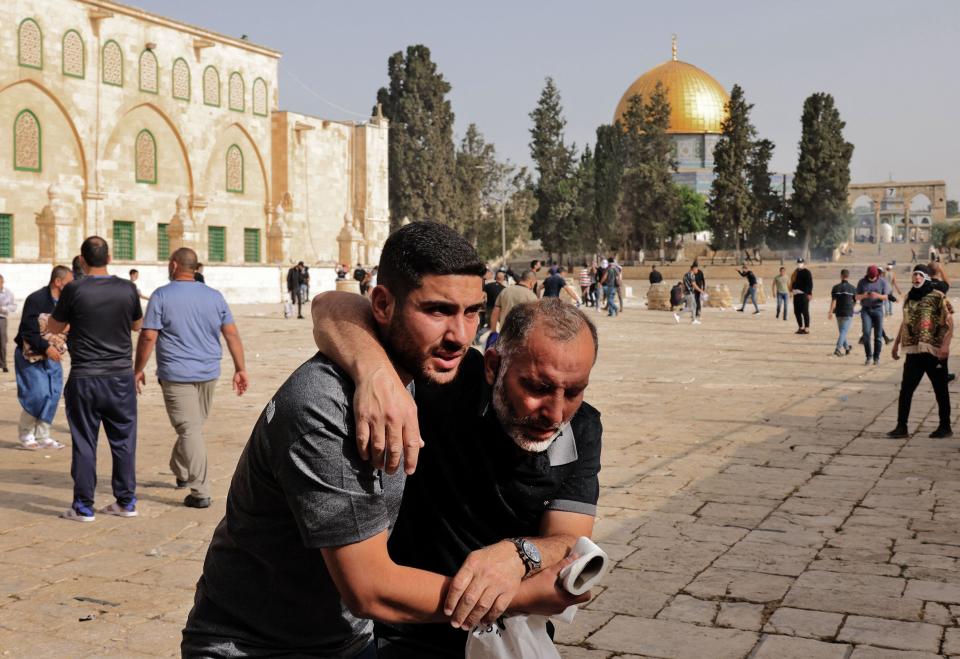 A Palestinian man helps a wounded fellow protester amid clashes with Israeli security forces at Jerusalem's Al-Aqsa mosque compound on May 10, 2021, ahead of a planned march to commemorate Israel's takeover of Jerusalem in the 1967 Six-Day War.