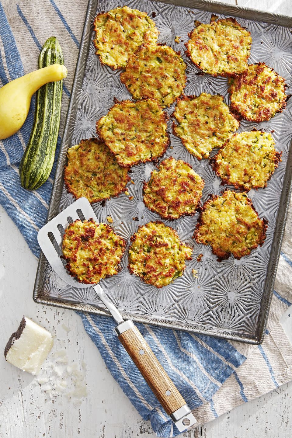 zucchini and pecorino fritters on a sheet tray with a spatula for serving