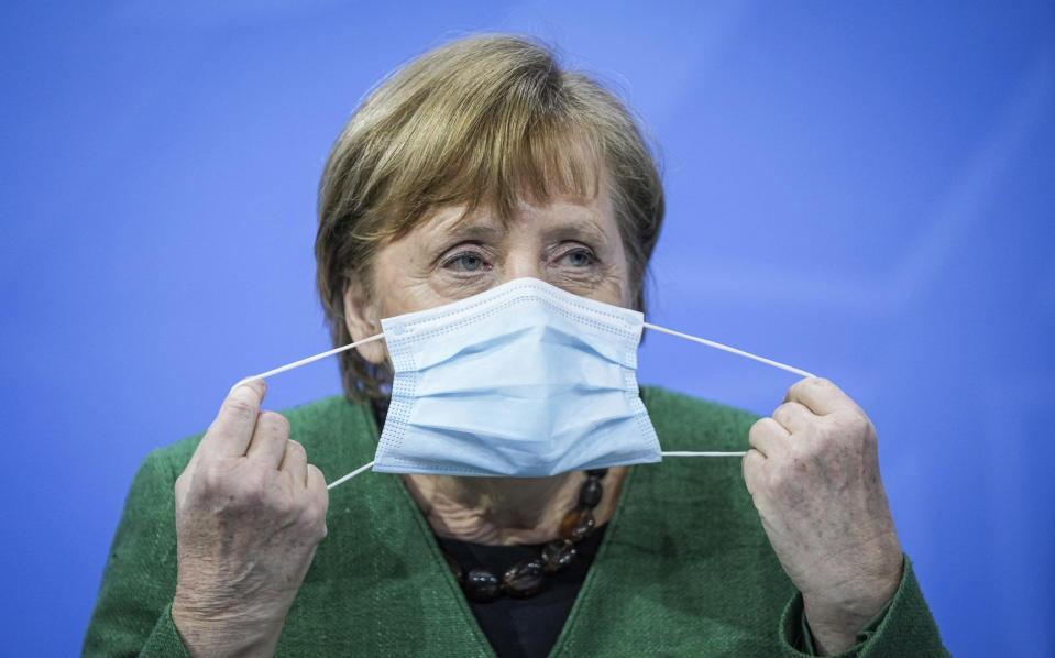 German Chancellor Angela Merkel removes her mask at the start of a press conference in the Chancellor's Office following consultations between the federal and state governments in Berlin Tuesday, March 23, 2021. Germany extended its lockdown measures by another month and imposed several new restrictions, including largely shutting down public life over Easter, in an effort to drive down the rate of coronavirus infections. (Michael Kappeler/Pool Photo via AP)