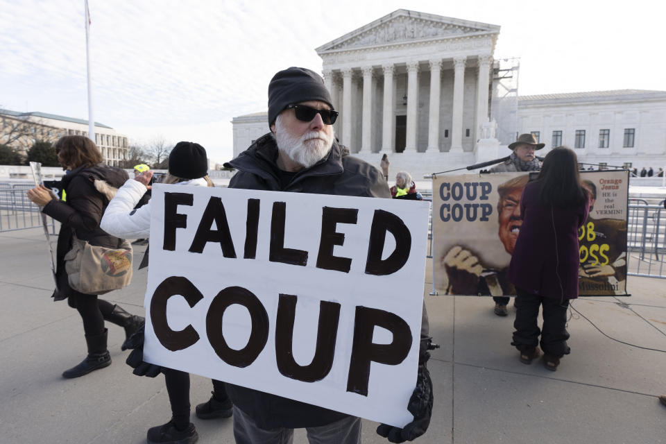 Bill Christeson holds a banner in front of the U.S. Supreme Court, Thursday, Feb. 8, 2024, in Washington. The U.S. Supreme Court on Thursday will take up a historic case that could decide whether Donald Trump is ineligible for the 2024 ballot under Section 3 of the 14th Amendment. (AP Photo/Manuel Balce Ceneta)