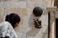 A woman walks past a bronze sculpture by Italian artist Alessandro Mutto at one of the Stations of the Cross along the Via Dolorosa, amid the coronavirus disease (COVID-19) outbreak in Jerusalem's Old City