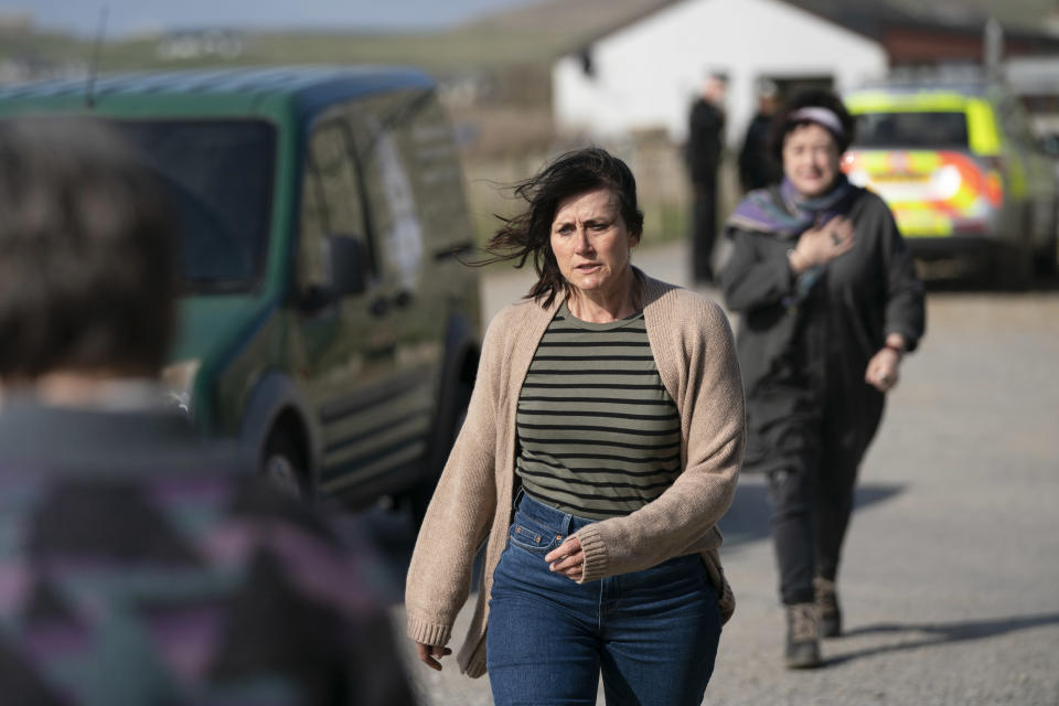 Stella Bain (Dawn Steele) is walking across a driveway looking intense with a police car out of focus in the background. Heather Bain (Lorraine McIntosh) is following her, a few steps behind.