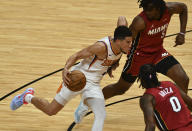 Phoenix Suns guard Devin Booker (1) splits the defense of Miami Heat forward Trevor Ariza (0) and forward Precious Achiuwa (5) during the second half of an NBA basketball game Tuesday, March 23, 2021, in Miami. (AP Photo/Jim Rassol)