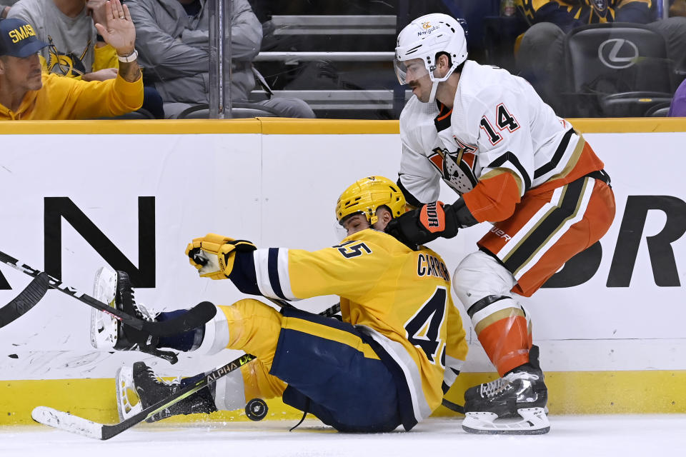 Nashville Predators defenseman Alexandre Carrier (45) and Anaheim Ducks center Adam Henrique (14) compete for the puck during the first period of an NHL hockey game Tuesday, Nov. 29, 2022, in Nashville, Tenn. (AP Photo/Mark Zaleski)