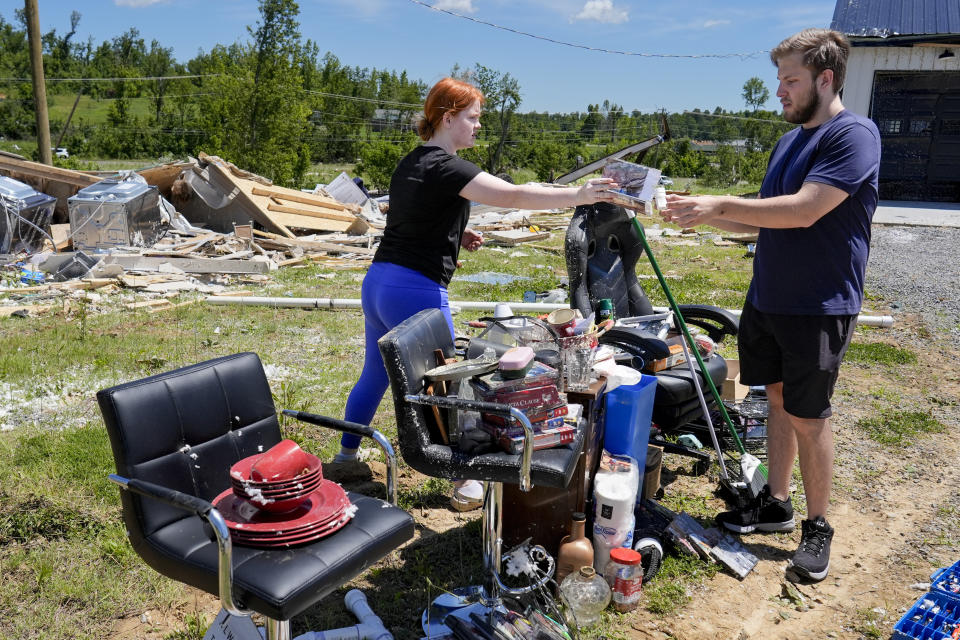 Haley Loukota, left, and her fiance Devin Johnson collect their belongings from storm debris after their home was demolished along Barnsley Loop, Tuesday, May 28, 2024, in Madisonville, Ky. A series of powerful storms hit the central and southern U.S. over the Memorial Day holiday weekend. (AP Photo/George Walker IV)