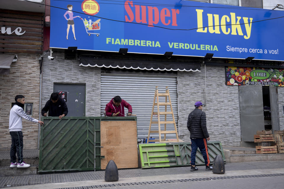 Supermarket owner Roger Oscosivi, center, welds a reinforced metal gate at the entrance of his store after threats of looting in Loma Hermosa on the outskirts of Buenos Aires, Argentina, Wednesday, Aug. 23, 2023. (AP Photo/Victor R. Caivano)