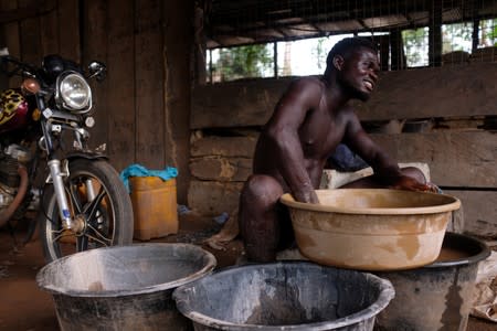 An informal gold miner mixes mercury with water and dirt in a plastic tub to extract gold at a site in Bawdie