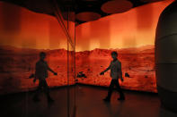 A woman walks past an exhibition depicting Mars landscape in Beijing on Friday, May 14, 2021. China says its Mars probe and accompanying rover are to land on the red planet sometime between early Saturday morning and Wednesday Beijing time. (AP Photo/Ng Han Guan)