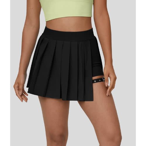 model wearing halara black pleated skirt with buckle garter and green crop top