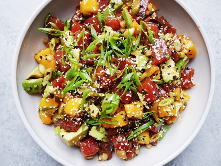 avocado mango poke salad topped with black and white sesame seeds and sliced green onion