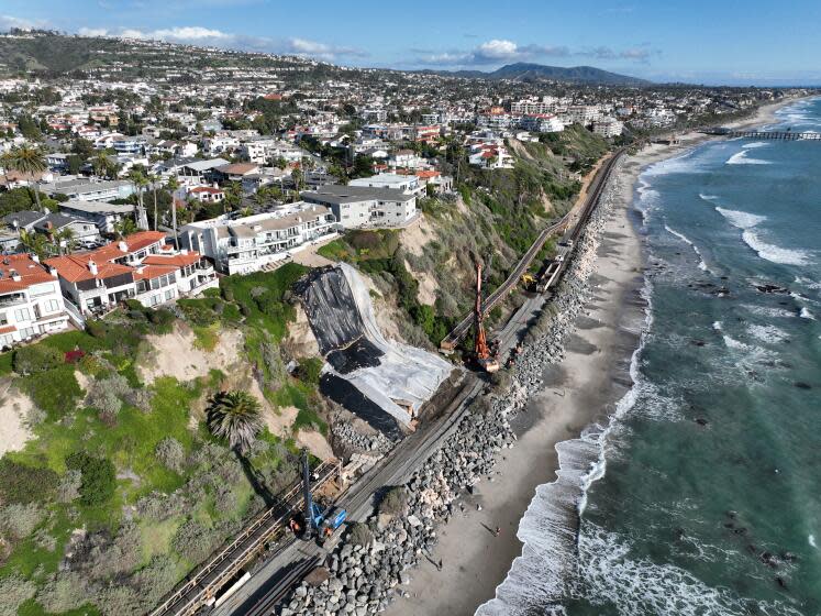 San Clemente, CA - February 27: An aerial view of a landslide near cliff-top homes, protective tarping to prevent further slides from upcoming rain storms and crews building a barrier wall to secure slipping slopes and protect the Metrolink tracks from sliding land in San Clemente Tuesday, Feb. 27, 2024. Multiple landslides have appeared on the ocean front bluffs in the North Beach area. The latest barrier wall will be the third built to secure San Clemente's slipping slopes and protect the tracks from sliding land. Costs are mounting for the continued slope failures. (Allen J. Schaben / Los Angeles Times)