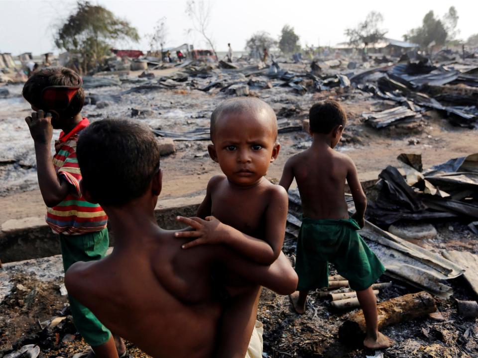 Boys stand among debris after fire destroyed shelters at a camp for internally displaced Rohingya Muslims in Rakhine (Reuters)